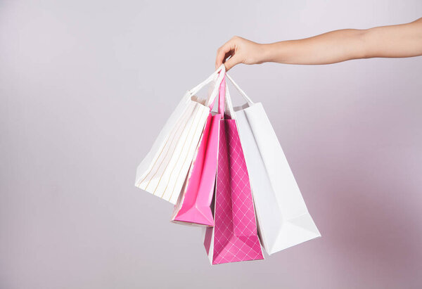 В руке девушки много бумажных пакетов..