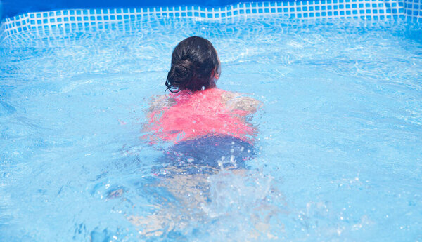 Девушка купается в бассейне. Солнечный день.