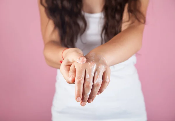 Genç bir kadın cildine doğal krem sürüyor..