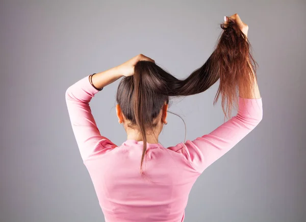 Jeune Fille Par Derrière Attachant Ses Cheveux Sur Fond Gris — Photo