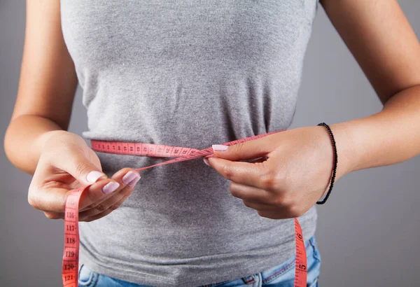 Diet woman measuring tape on gray background. Weight loss concept.