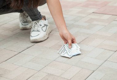 Kayıp para konsepti. Kadın yerden parasını alıyor..