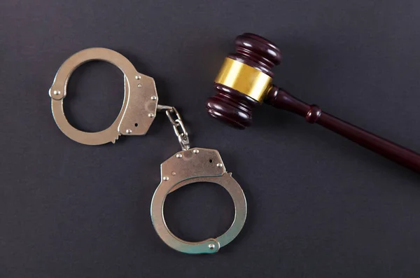 Polis kelepçeleri ve hakim tokmağı izole edilmiş siyah bir arkaplanda..
