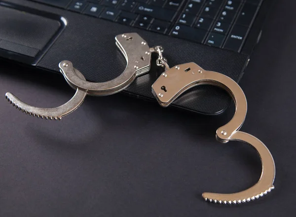 Polis metali kelepçeler ve bilgisayar klavyesi.