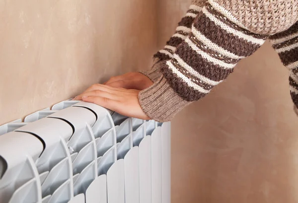 Young woman near electric heater at home.