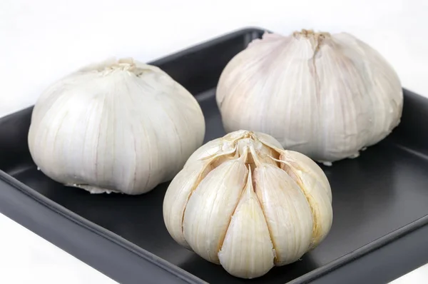 Πρώτων υλών και ξεφλουδισμένες σκόρδο στο Μπαλκ πιάτο σε λευκό — Φωτογραφία Αρχείου