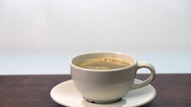 Adding whole 3 organic sugar cube in hot ceramic coffee cup on white saucer, on wooden table morning beverage, hot aromatic coffee, minimal style, inviting and cozy breakfast refreshment