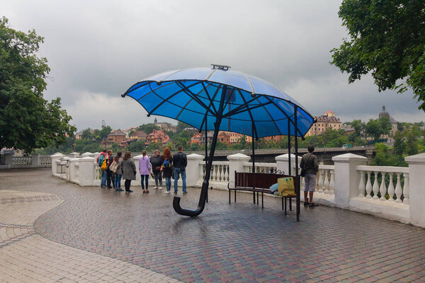 Kamyanets-Podolsky, Ukraine - June 30, 2018: Tourists on a rainy day by the bridge in the center of the city