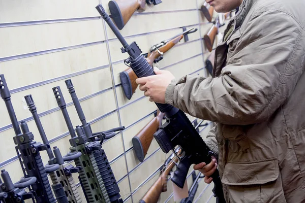 Un hombre con un rifle automático en la tienda. Armas. —  Fotos de Stock