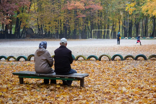 Couple of elderly people sit on a bench in the autumn Park. People