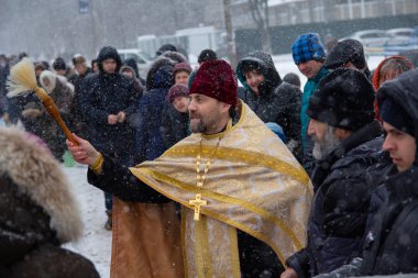 Kiev, Ukrayna - 18 Ocak 2018: Rahip cemaat kilisenin kutsal su ile vaftiz Ortodoks tatil kutlamaları sprinkles.