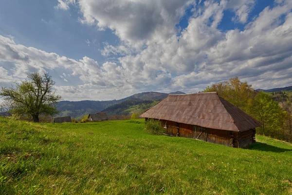 Alte Hütte auf einer grünen Wiese vor dem Hintergrund der Berge. Karpaten — Stockfoto