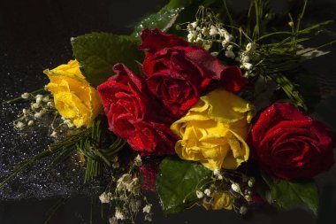 Bir ayna siyah yüzey üzerinde kırmızı ve sarı güller. Çiçekler