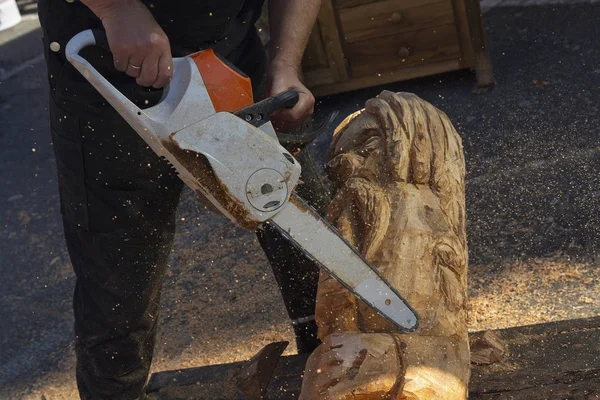 O homem com uma motosserra cria uma escultura feita de madeira. Escultura em madeira — Fotografia de Stock