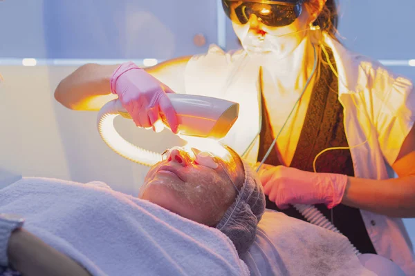 Eliminación láser de la decoloración de la piel en la cara.Clínica cosmética, mujer durante la cirugía facial con láser — Foto de Stock