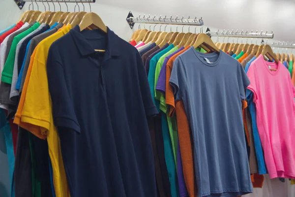 Variedade de camisetas de cores diferentes em cabides de madeira — Fotografia de Stock