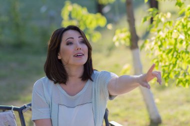 Güzel duygusal kadın işaret parmak bankta oturan. Insanlar