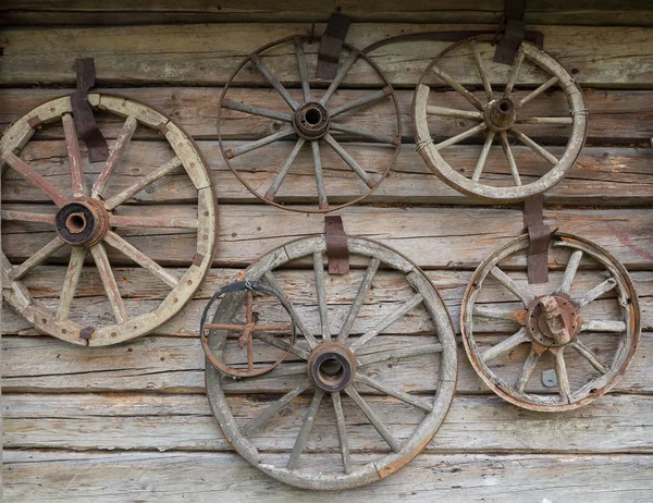 Rodas de madeira de um carro antigo pendurado na parede da cabana — Fotografia de Stock
