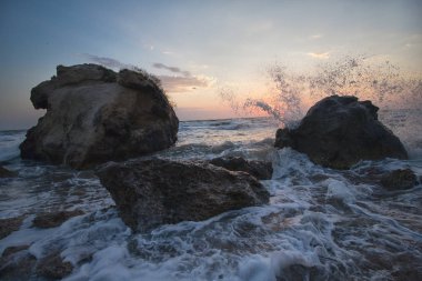 Gün batımında dalgalar plajda kayalara vuruyor. Kırım