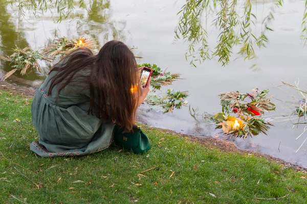 Девушка фотографирует венок в озере, исполняя традиционный обряд славянского праздника Ивана Купалы — стоковое фото