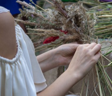 Bir kızın elinde tarla otlar ve çiçekler geleneksel çelenk. Ivan Kupala kutlama ayini için hazırlanıyor