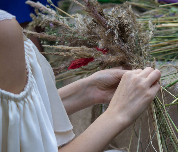 Traditional wreath of field herbs and flowers in the hands of a girl. Preparing for the rite of celebration of Ivan Kupala