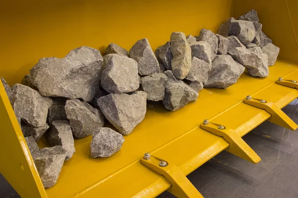 Construction excavator bucket and stones in the showroom. Industry — Stock Photo, Image