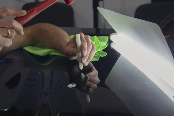 Arabanın düzleştirilmesi üzerinde çalışan işçinin elleri. Araba servisi