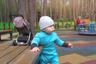 Çocuk serin havada parktaki oyun alanında oynar. İnsanlar