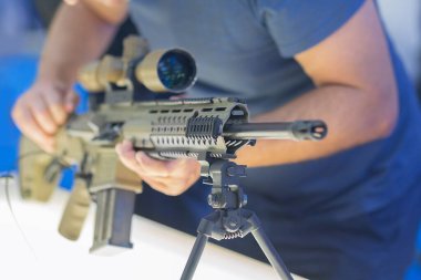 Bir adam bir silah dükkanında saldırı tüfeğini inceliyor. Silahlar.