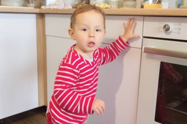 Ev mutfağındaki fırının yanında tatlı bir çocuk var. İnsanlar