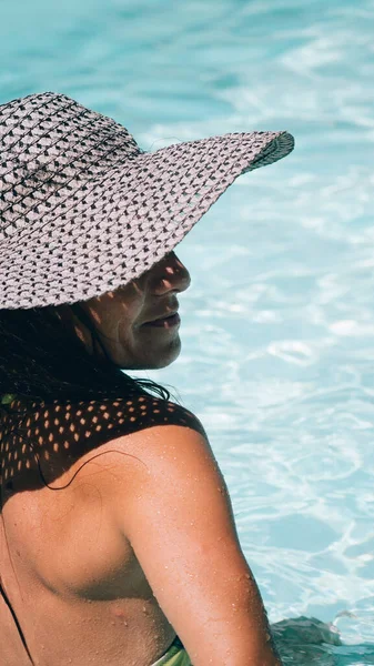 Güneşli bir günde havuzda bikini banyosu yapan gülen kadın. Yan tarafa bakıyor..