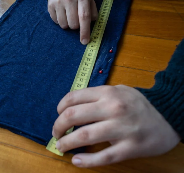 Mujer con un centimetro toma medidas de una tela en el suelo. Trabajo de costureria.