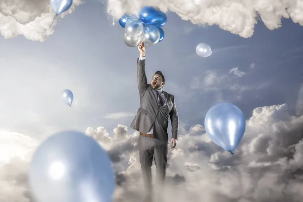 Businessman reacing balloons — Stock Photo, Image