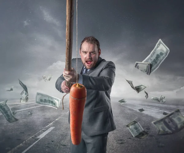 Podnikatel, drží mrkev v tyči — Stock fotografie