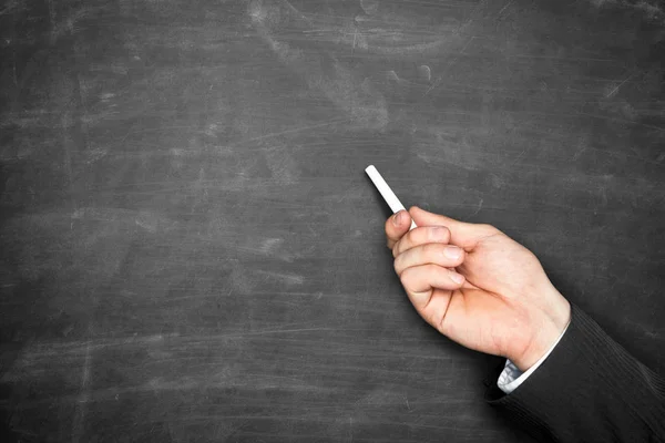 Businessman hand holding chalk and pointing on blackboard — Stock Photo, Image