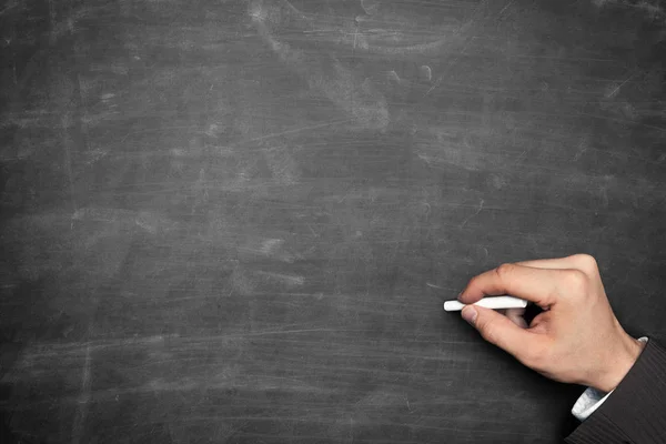 Businessman hand holding chalk and pointing on blackboard — Stock Photo, Image