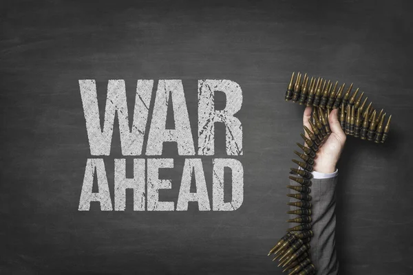 War ahead text on blackboard with businessman hand holding ammunition — Stock Photo, Image