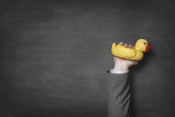 Pato de baño en mano de hombre de negocios con fondo de pizarra — Foto de Stock