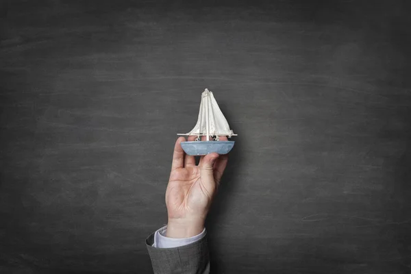 Businessman holding a toy boat in hand