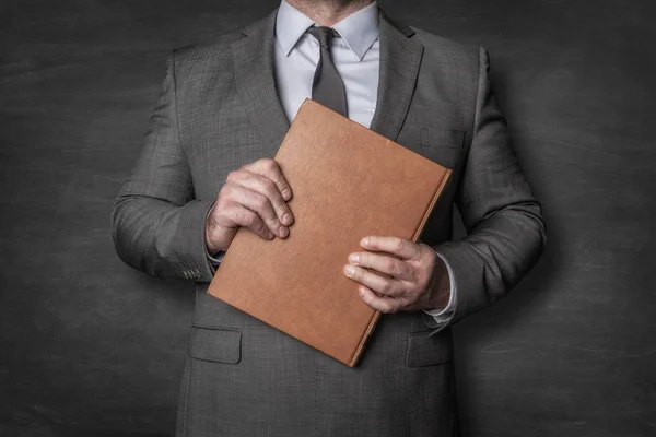 Empresario sosteniendo un libro delante de él — Foto de Stock