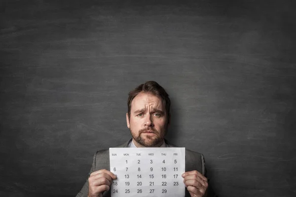 Geschäftsmann zeigt Papierkalender vor sich — Stockfoto