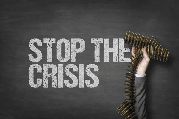 Stop the crisis text on blackboard with businessman hand holding ammunition — Stock Photo, Image