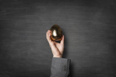 Bir altın yumurta bir elinde tutan işadamı