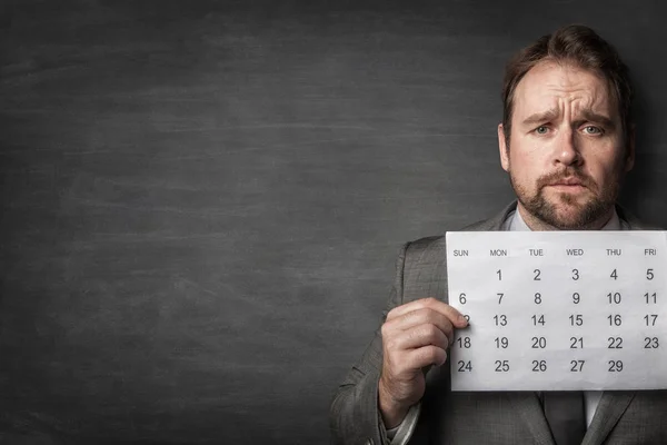 Empresario mostrando el calendario de papel delante de él Imagen De Stock