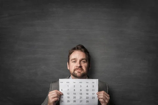 Geschäftsmann zeigt Papierkalender vor sich — Stockfoto