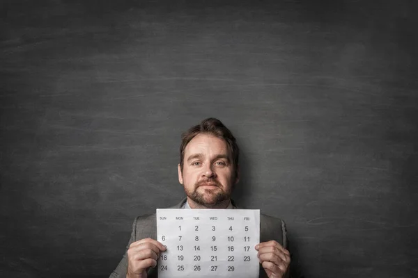 Empresario mostrando el calendario de papel delante de él Imagen De Stock