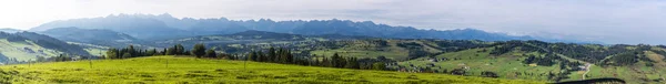 A huge, wide panorama with the autumnal landscape of the Tatra Mountains and the Bukowina Tatrzanska tourist village lying at their foot. — Stock Photo, Image