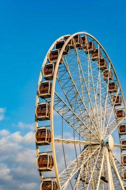 Krakow, Polonya - 11 Temmuz 2020: Dönme dolap mavi gökyüzüne karşı sabah güneşinin altında bulutlarla.