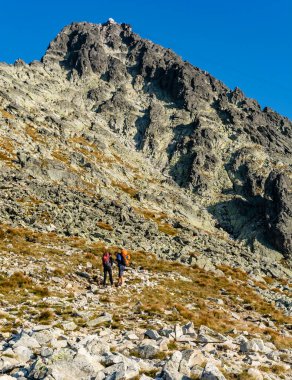 Tatranska Lomnica, Slovakya - 15 Eylül 2020: Rehberde Lomnica zirvesine tırmanmanın tanımını okuyan iki turist.